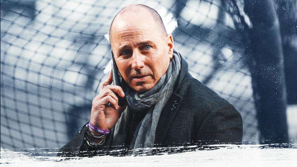 Yankees GM Brian Cashman treated image, on phone wearing coat with blue/grey background