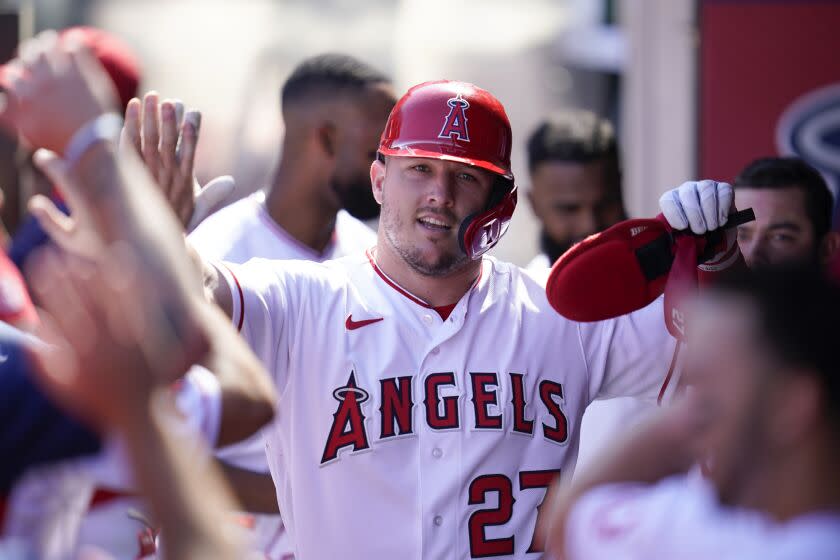 Los Angeles Angels' Mike Trout (27) celebrates in the dugout after scoring off of a single hit by Taylor Ward.