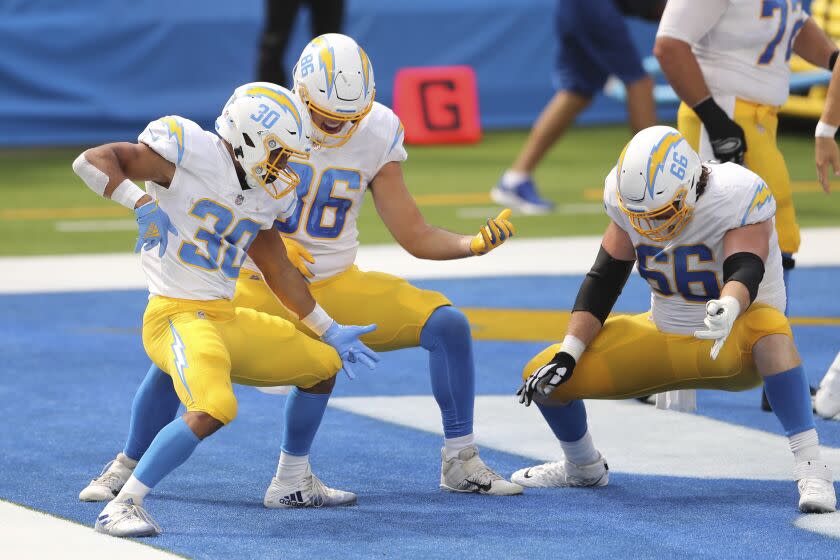 Los Angeles Chargers running back Austin Ekeler (30) follows his touchdown with a ai guitar celebration with Los Angeles Chargers tight end Hunter Henry (86) and Los Angeles Chargers center Dan Feeney (66) during an NFL football game against the Carolina Panthers, Sunday, Sept. 27, 2020, in Inglewood, Calif. (AP Photo/Peter Joneleit)