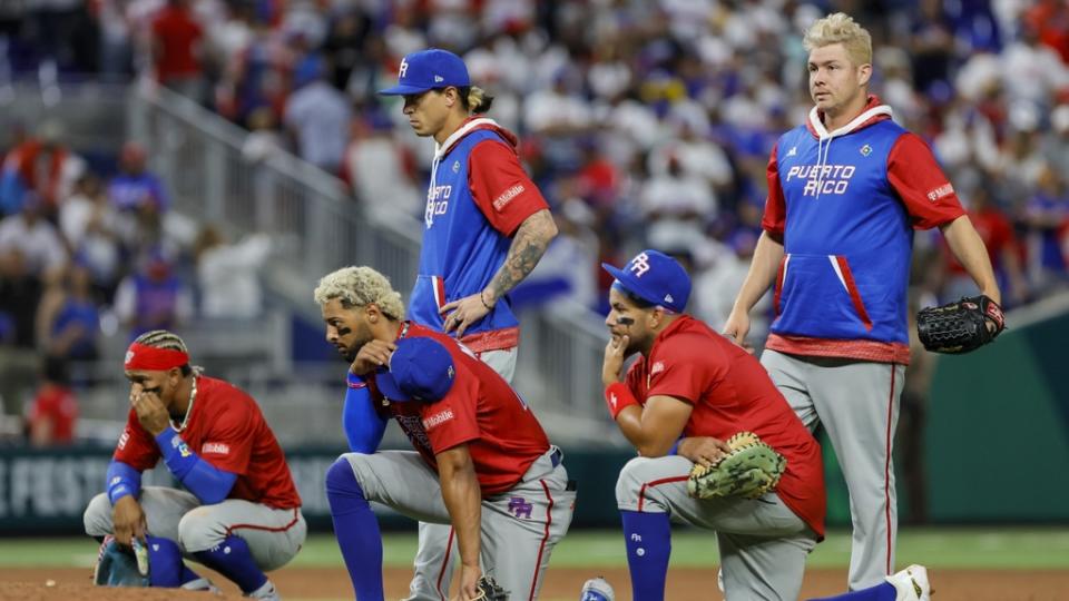 Mar 15, 2023; Miami, Florida, USA; Puerto Rico players take a knee as pitcher Edwin Diaz (not pictured) gets checked on by training staff after an apparent leg injury during the team celebration against Dominican Republic at LoanDepot Park.