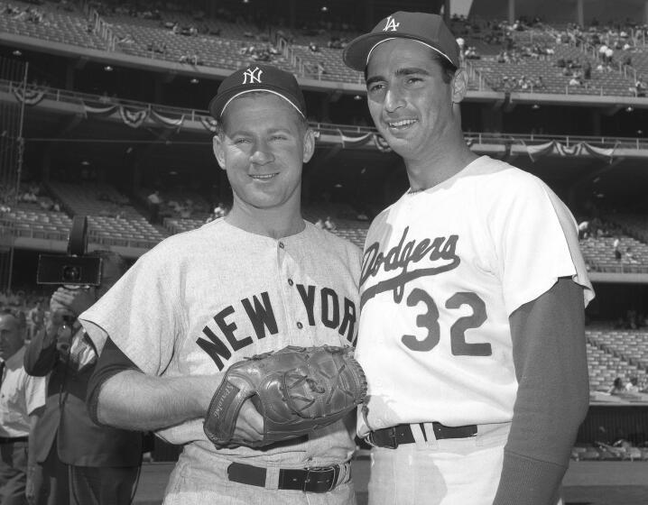 Two men in baseball uniforms, one wearing a glove, pose together for a photo.