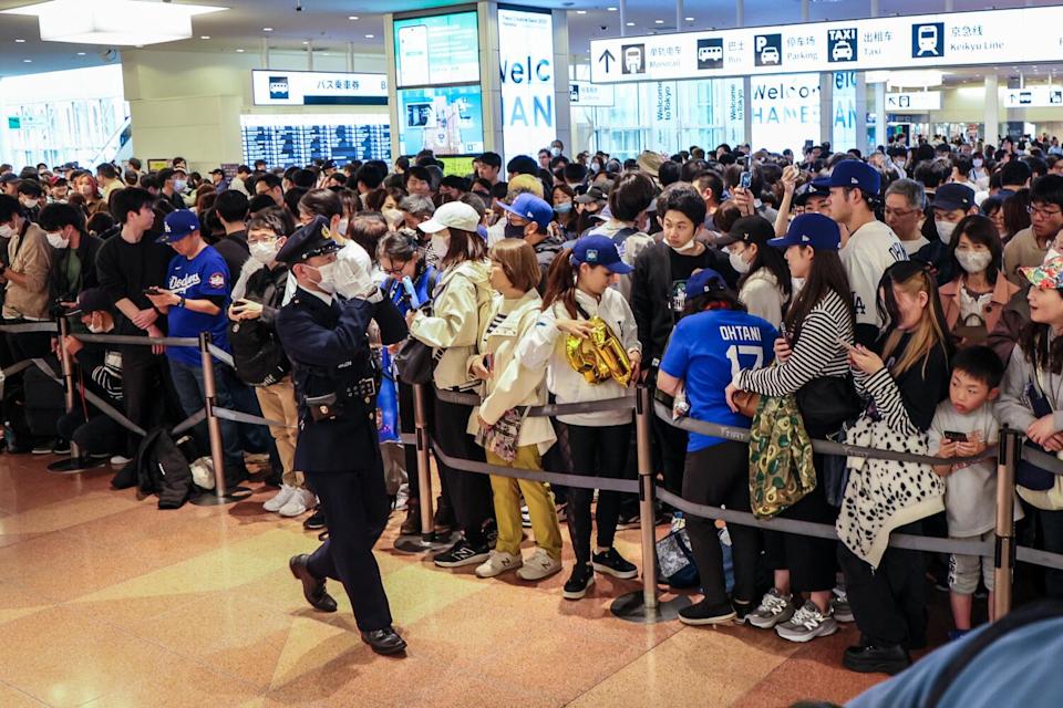 A police official announces to fans gathered at Haneda Airport that the Dodgers had arrived at another terminal Thursday.